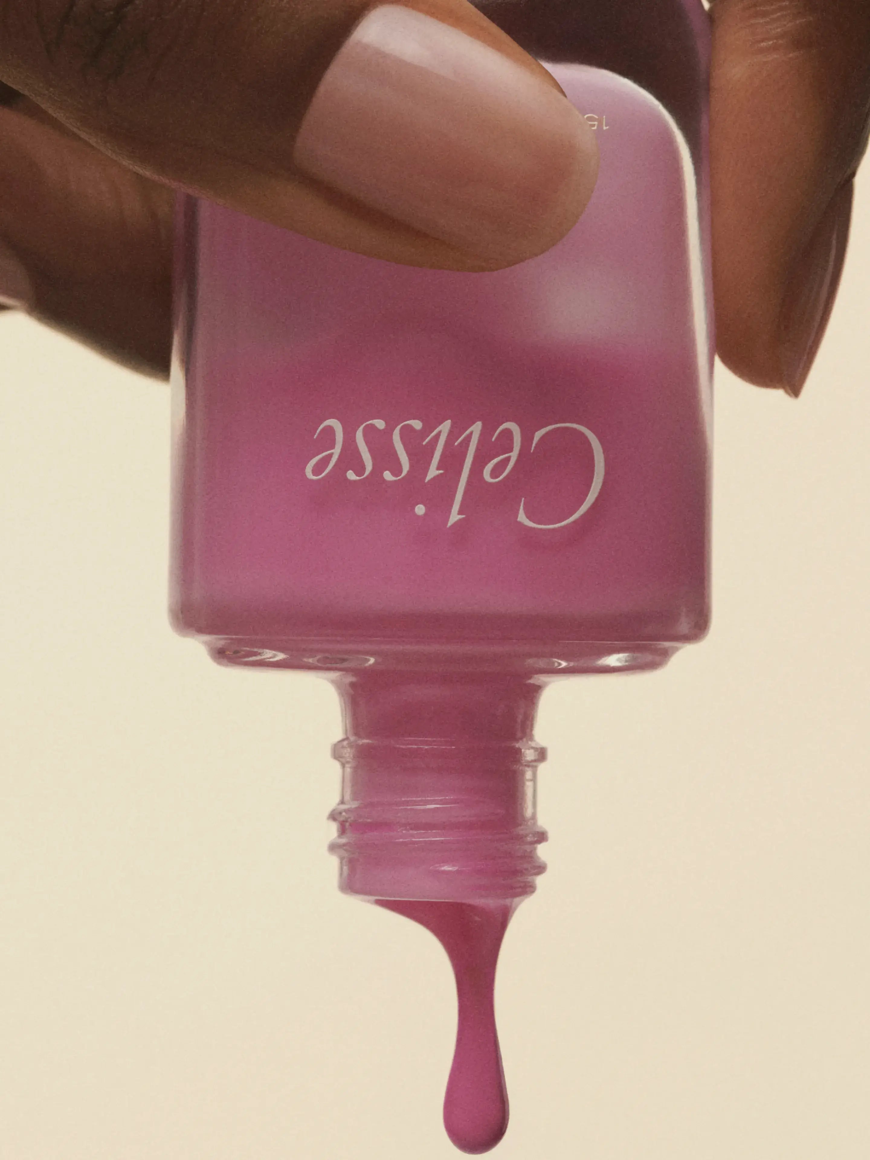Pink nail polish bottle with 'Celisse' branding held by a hand against a beige background